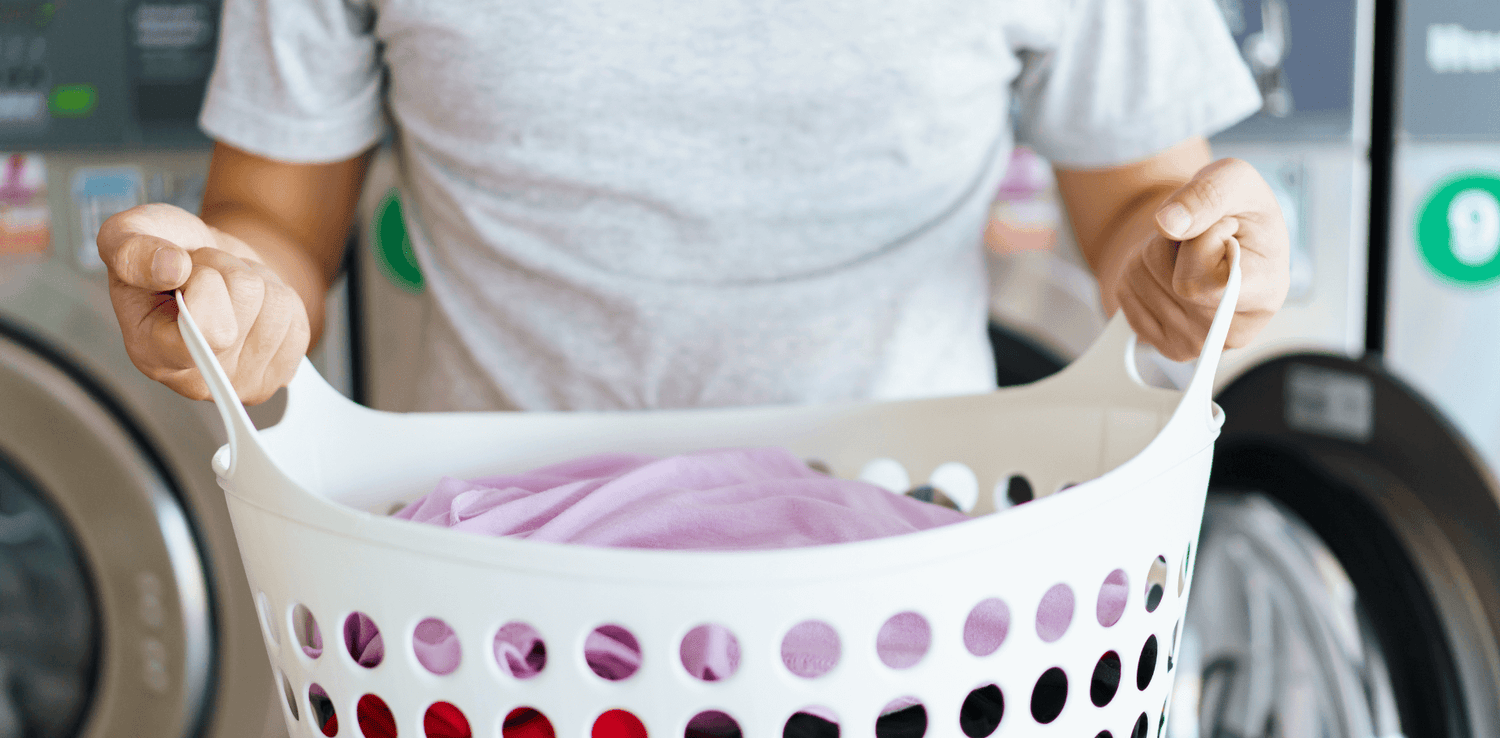 A man holding a basket of dirty laundry.